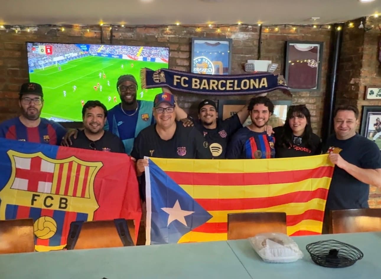 Charm City Culés members posing with FC Barcelona and Catalan flags