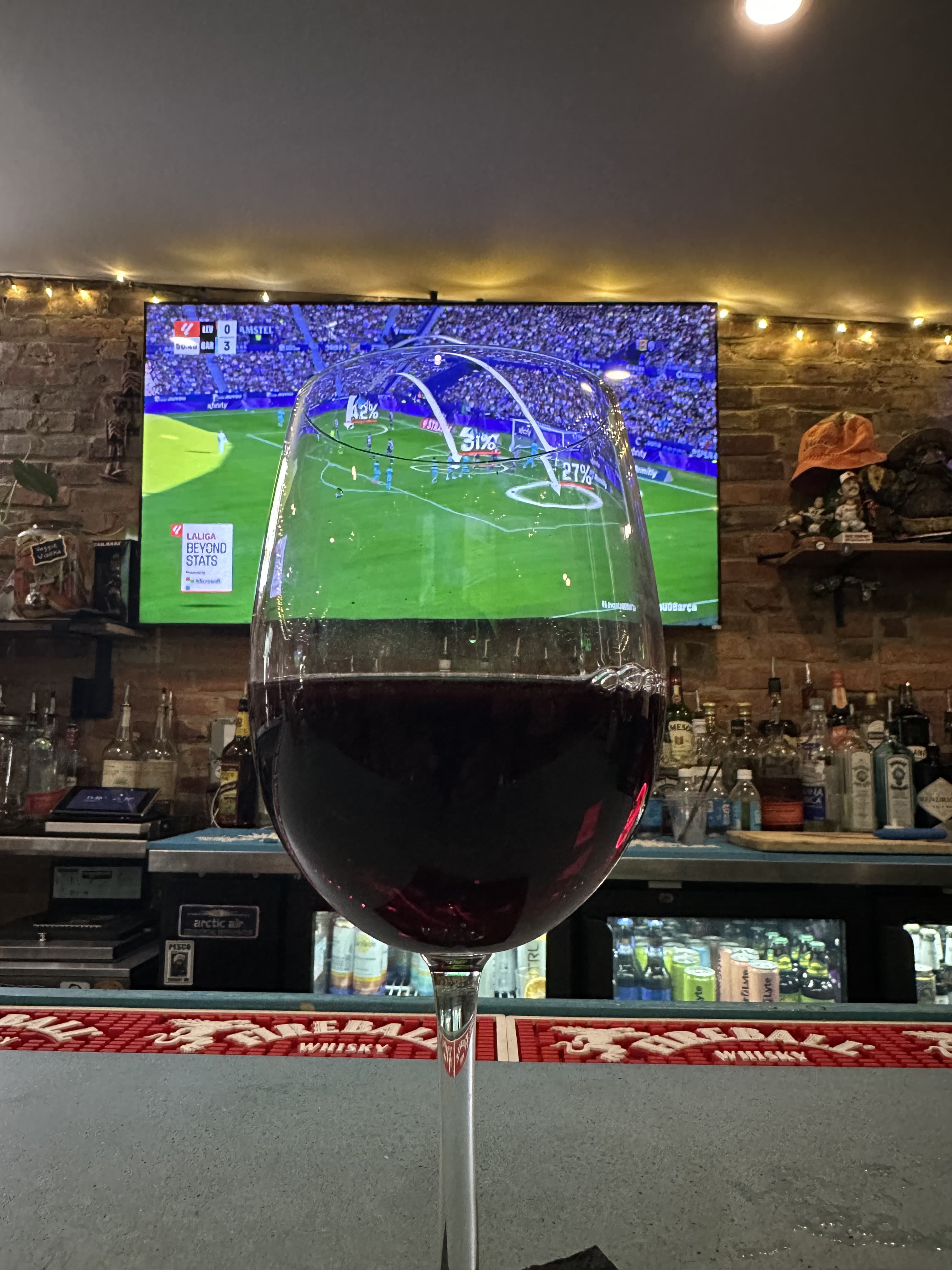 Glass of red wine in front of a televised FC Barcelona match